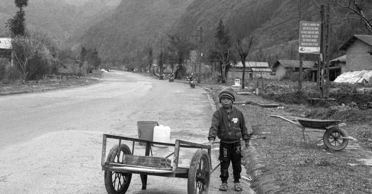 To lid or not to lid? - Grayscale Photo of Man in Jacket Sitting on Bench Near Mountain