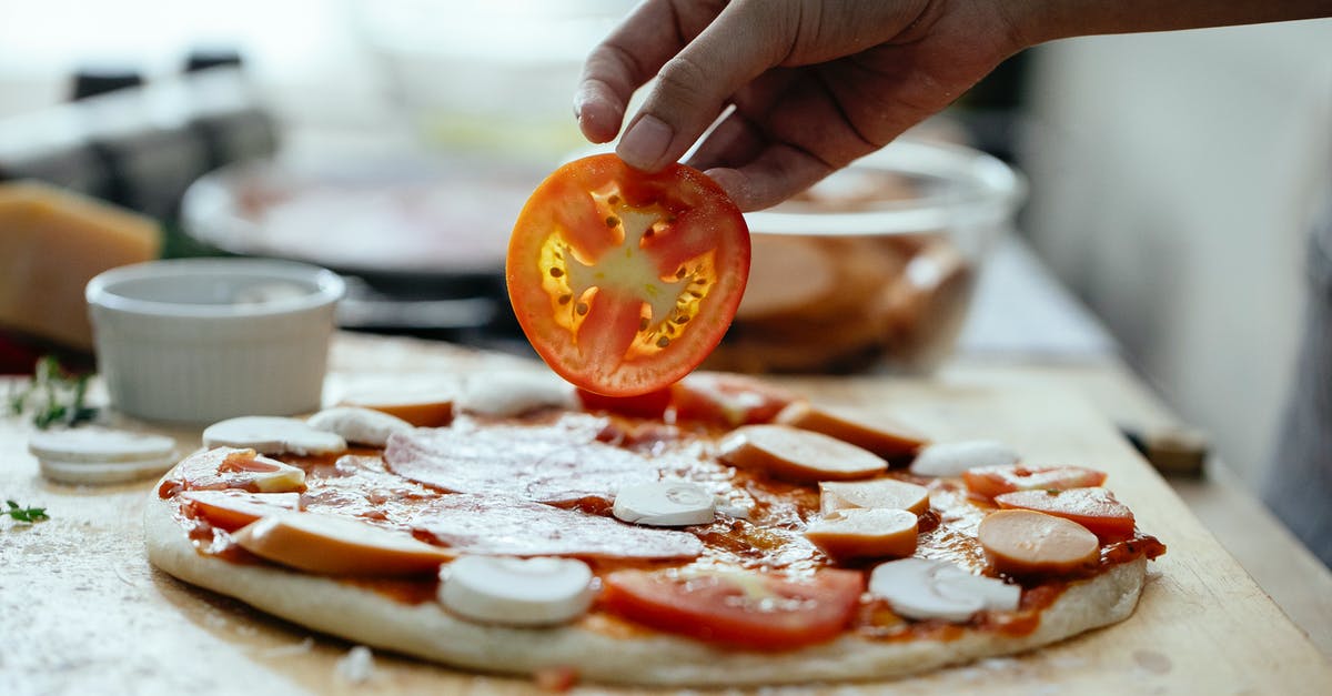 To put aromatics at beginning or end of cooking? [closed] - Unrecognizable person adding tomatoes in pizza
