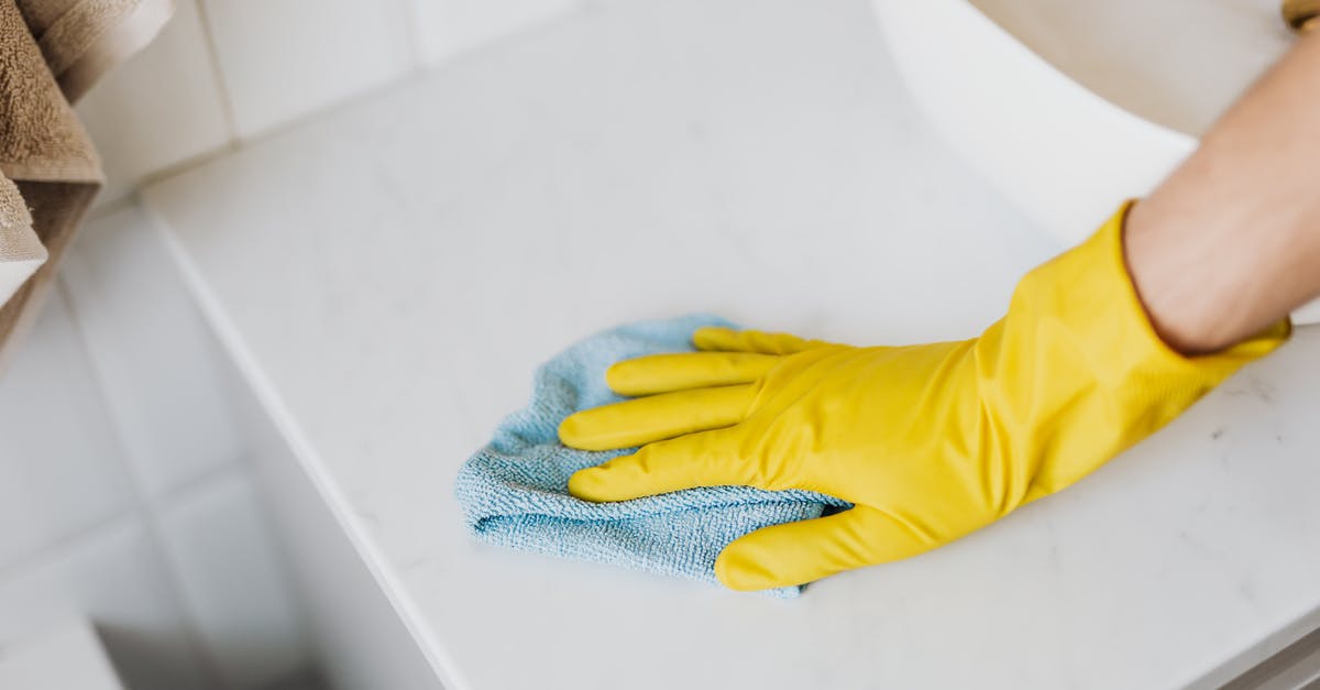 to remove casing from sausages or not? [duplicate] - From above crop unrecognizable person with microfiber cloth wearing yellow rubber glove and cleaning white marble tabletop of vanity table with washbasin in bathroom