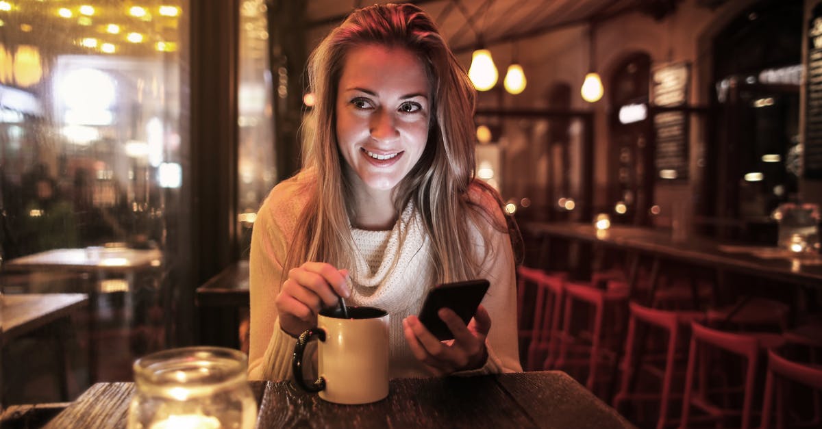 Too much wine used in coq au vin - Delighted woman with cup of beverage browsing smartphone in cafe