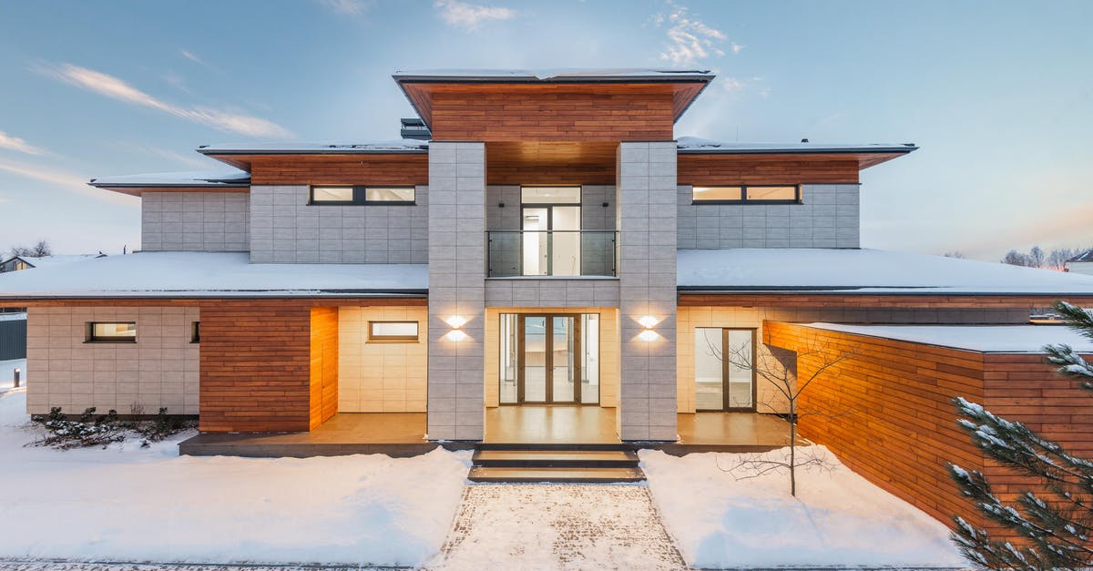 Trimming ends off snow peas - Backyard view of new modern luxurious cottage house with stone and wooden facade and illumination in winter countryside