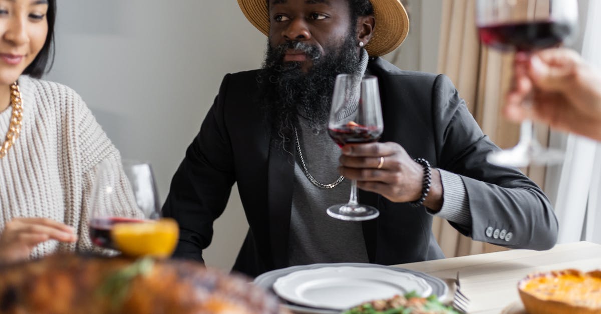 Turkey Dinners For A Group of 140 People - Positive diverse adult friends drinking wine while sitting at table served with delicious dishes and celebrating Thanksgiving Day