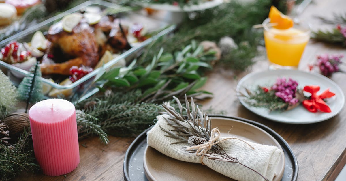 Turkey vs Chicken broth - High angle of table served for Christmas dinner with plates with napkins and traditional roasted turkey on glass dish decorated with fir twigs