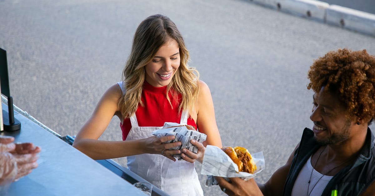 Turkish delight sauce or syrup - From above of positive multiethnic couple eating tasty burgers wrapped in paper at food truck