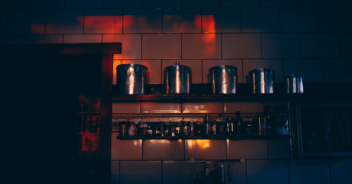 underfilled whipper canisters - Low angle of stainless steel canisters placed in row on shelf in dark kitchen with tile walls