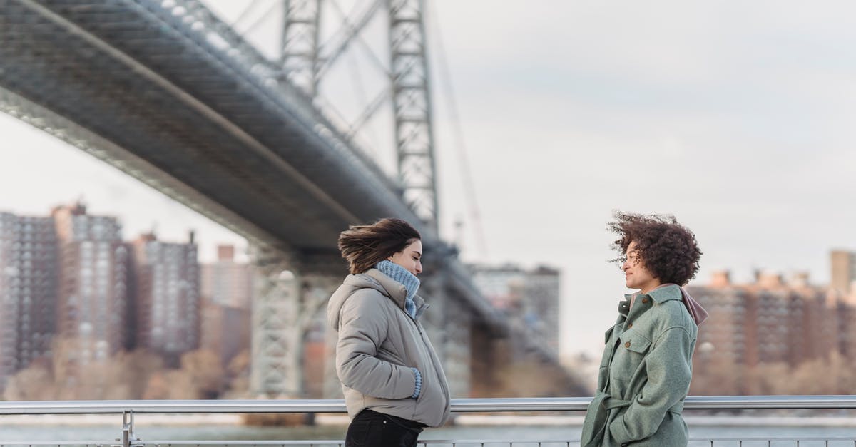 Units conversion : cl to grams - Side view young female friends in warm clothes having conversation and standing face to face on New York City embankment on cold winter day