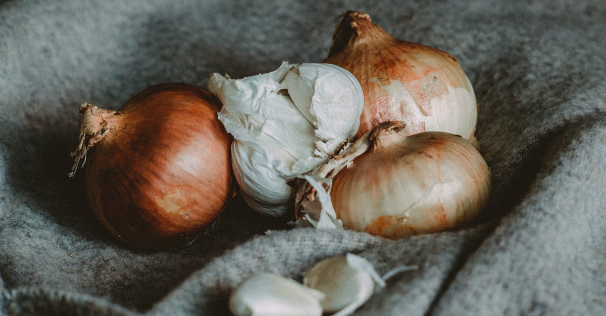 Unpeeled garlic cloves in French / Belgian cooking? - High angle of unpeeled golden onions and garlic bulb placed on soft plaid in kitchen