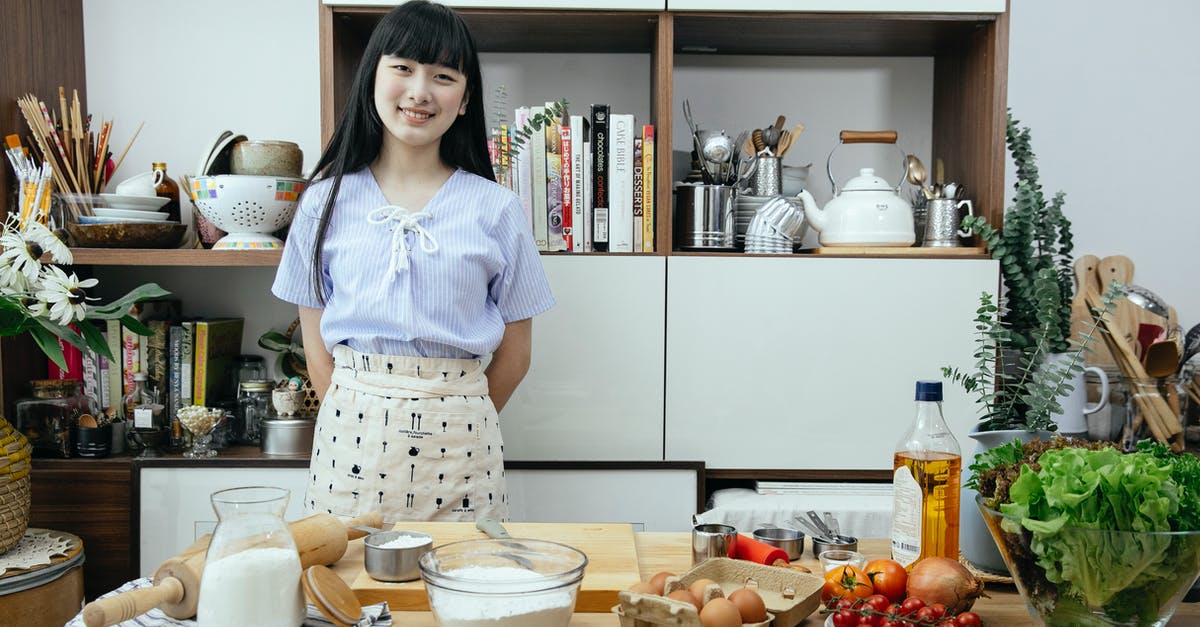 Use flour vs oil in rising dough - Happy young Asian woman standing near table with ingredients for dough