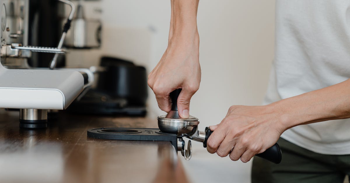Using a French press with finely ground coffee - Crop professional barista preparing coffee at wooden counter