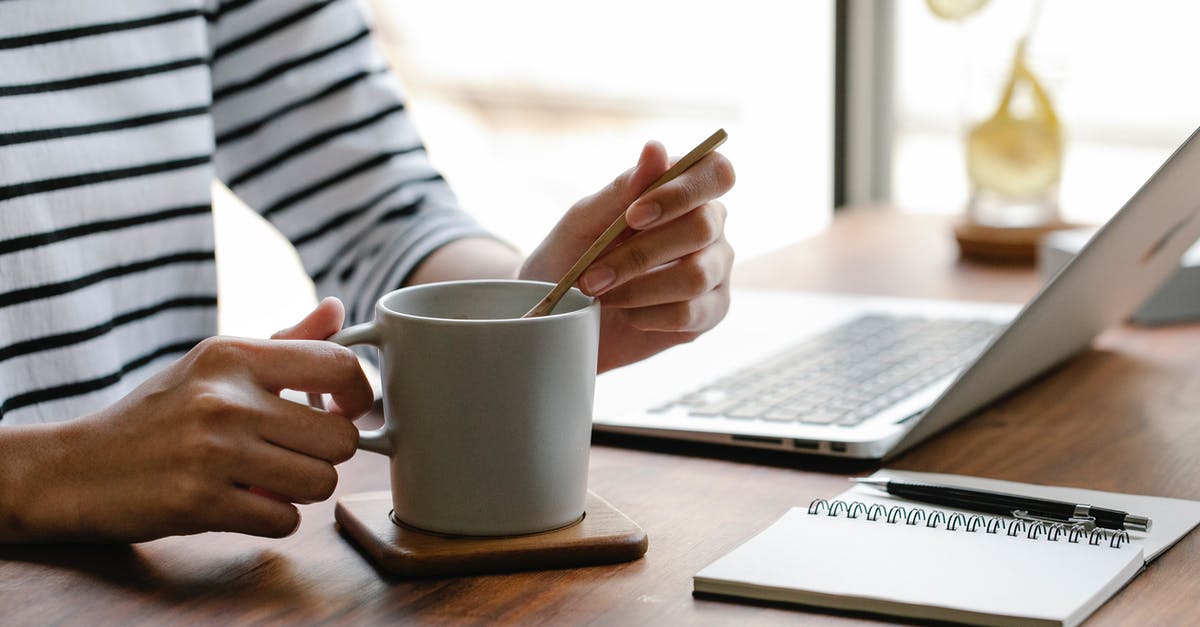 Using a wooden spoon to prevent pots from boiling over? - Crop unrecognizable freelancer in casual clothes sitting at table with white cup of hot drink near laptop and notebook