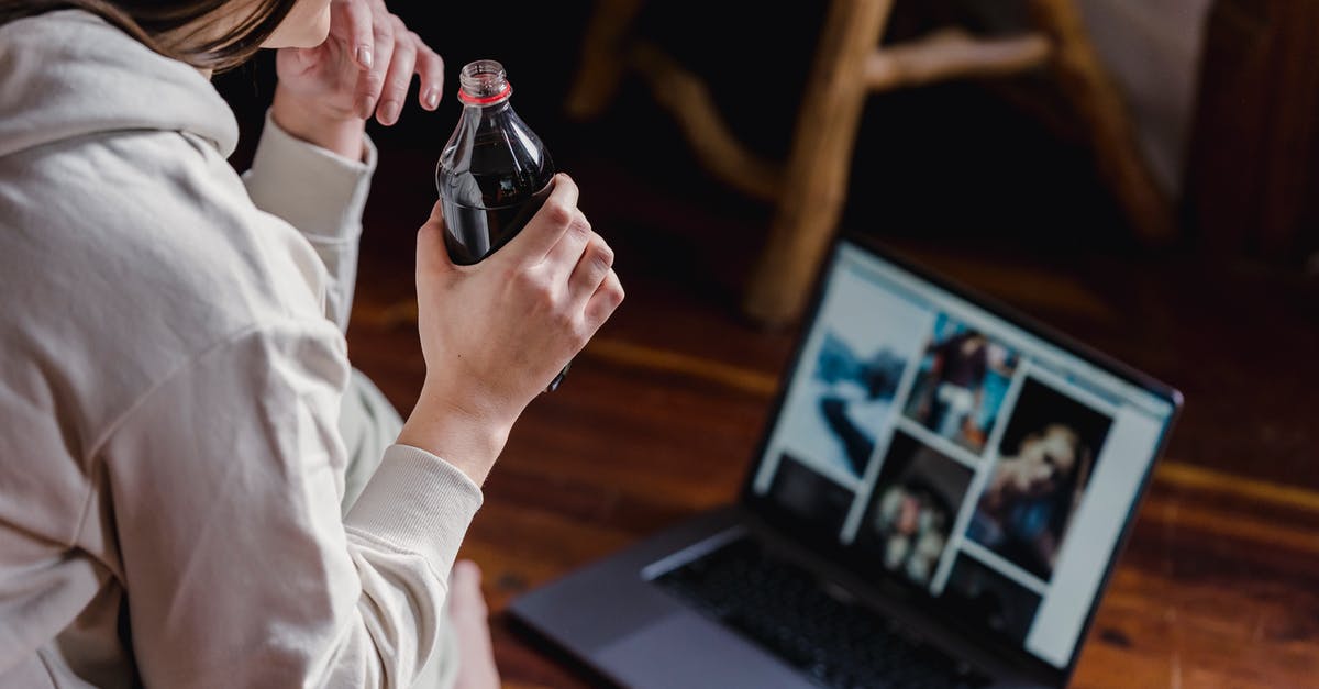 Using baking soda - Crop woman with bottle of soda sitting on floor with laptop