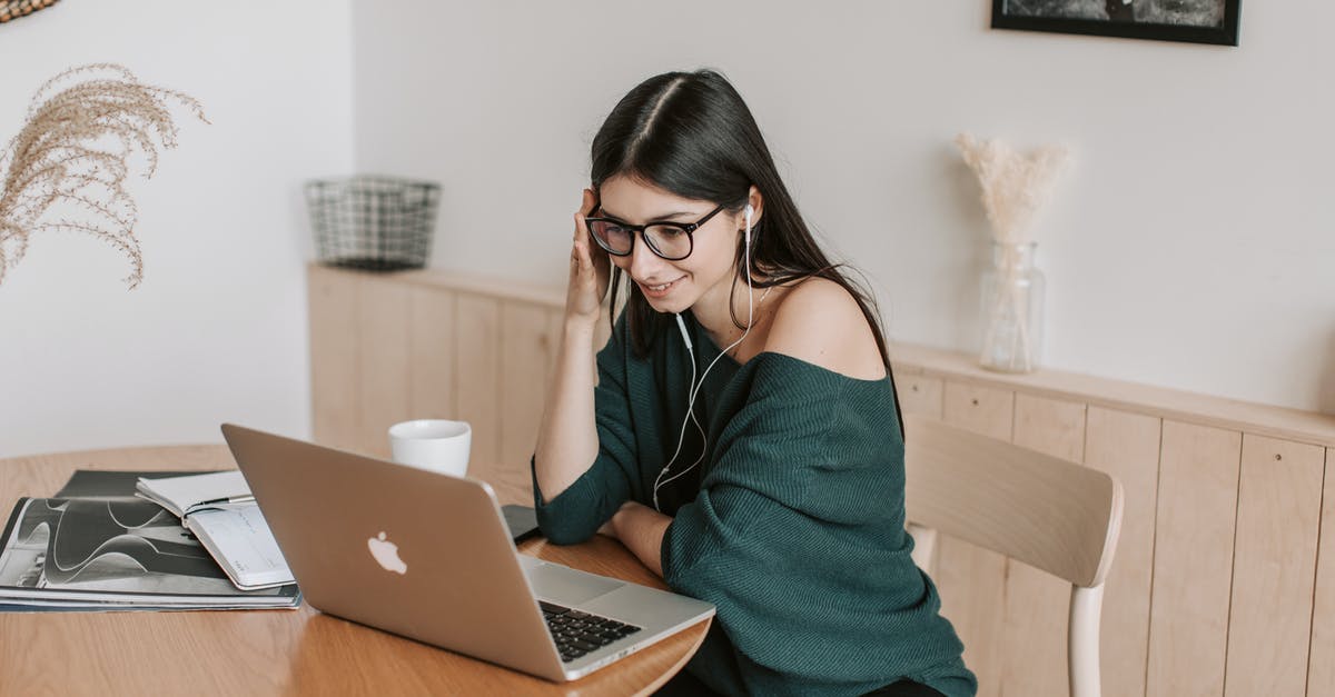 Using decorative loaf pans - Smiling student in earphones watching laptop at table at home