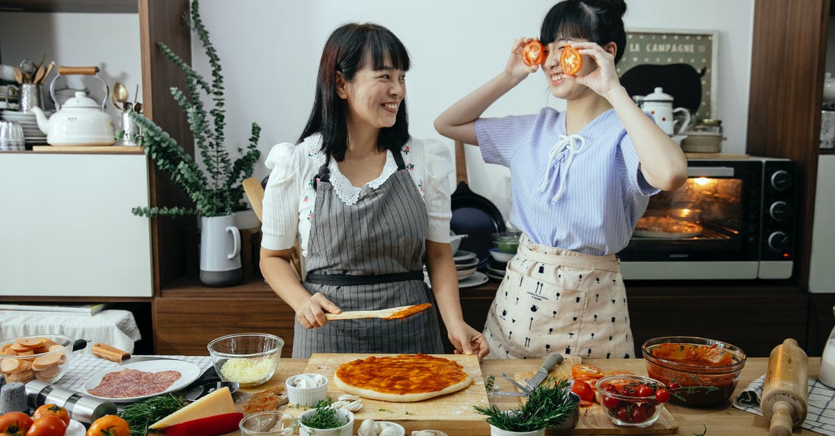 Using over-rested pizza dough as old dough - Positive women having fun cooking pizza