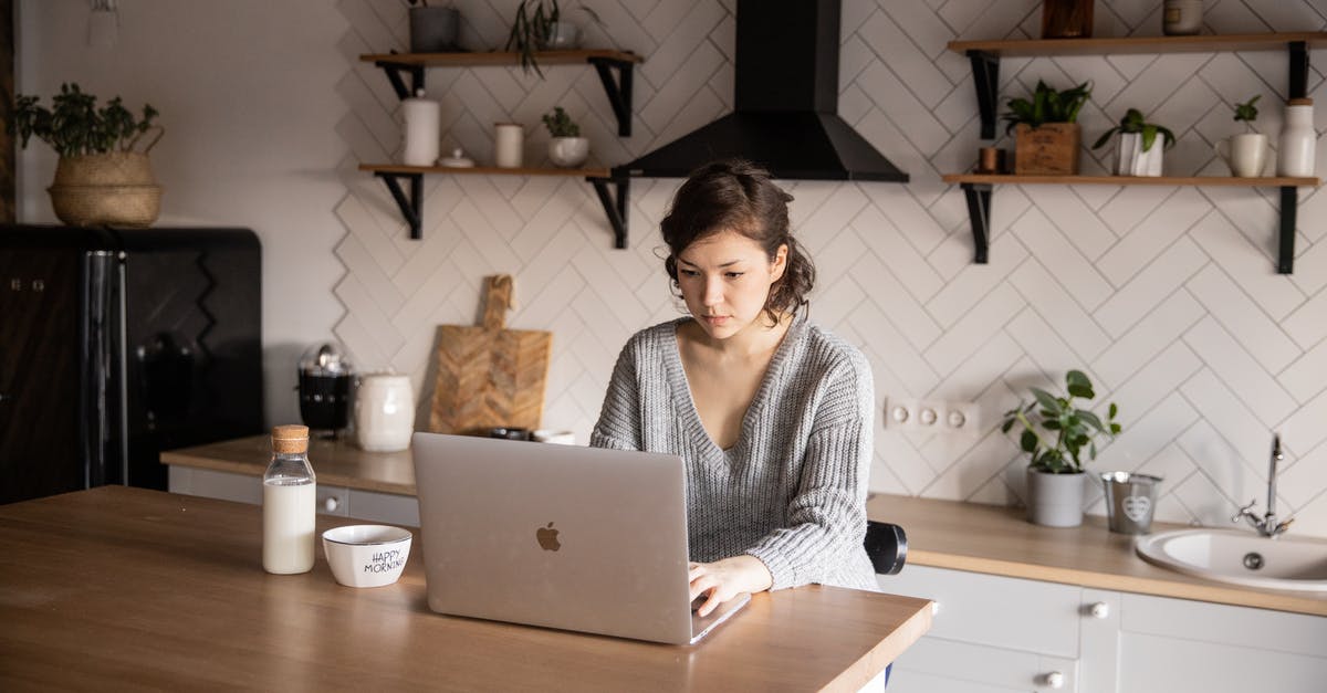 Using skim or low-fat milk in recipes - Content young woman browsing laptop in modern kitchen