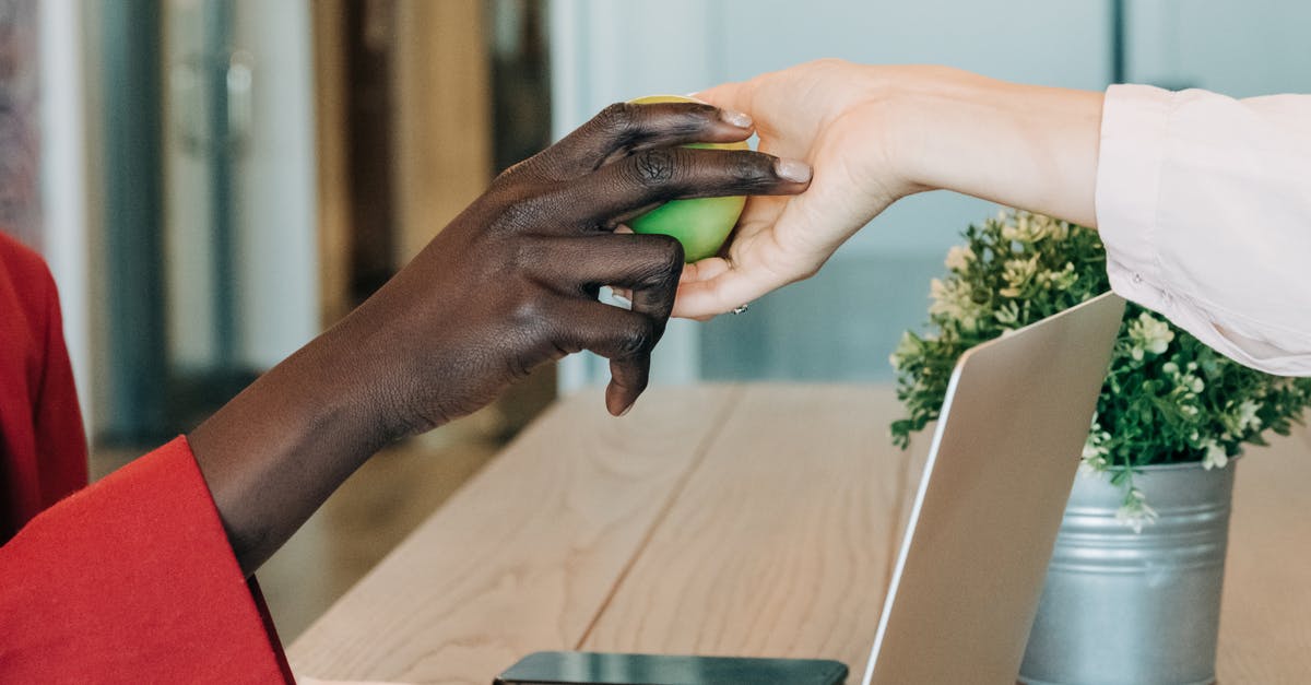 Using soft apples to make apple juice - Black businesswoman taking green apple from colleague at workplace