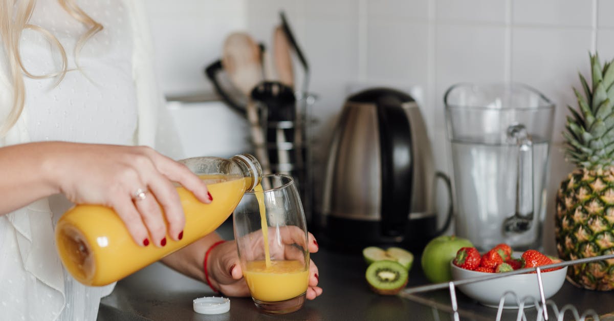 Using soft apples to make apple juice - Crop woman poring juice standing near table with fruits