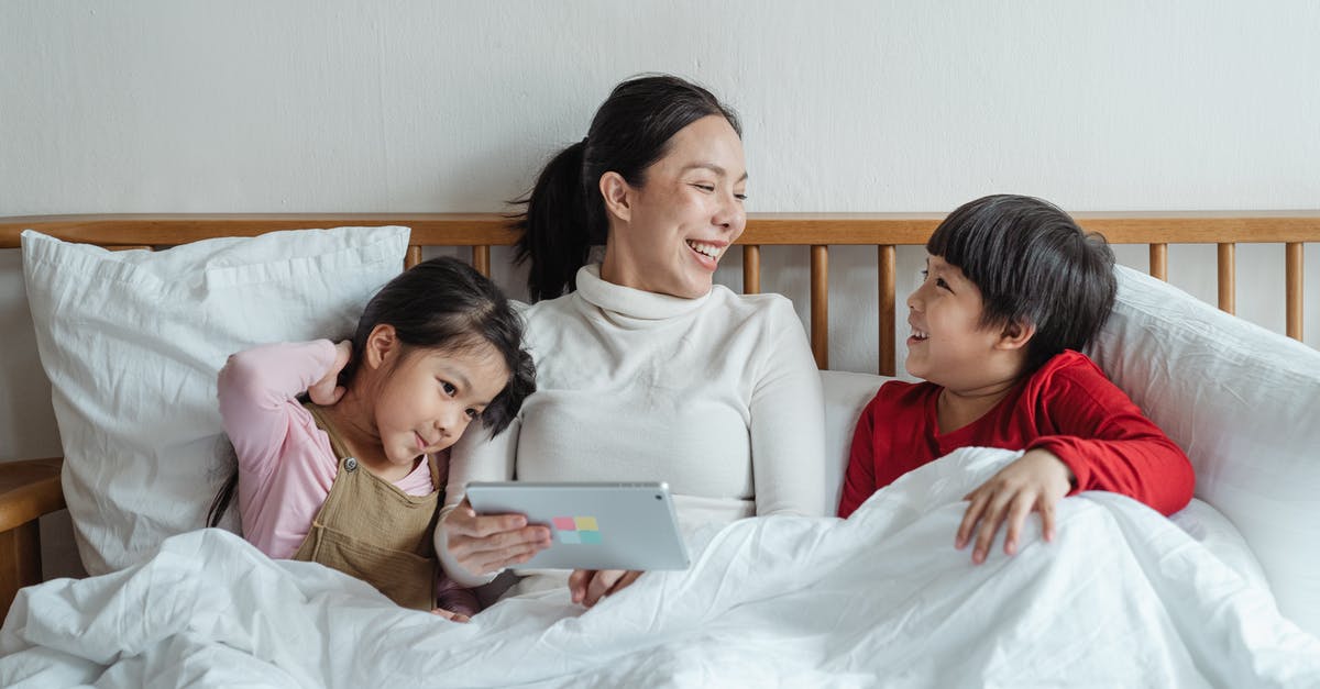 Using yeast that's been proofed - Positive ethnic mother and little daughter and son having fun together in cozy bed in morning while using tablet