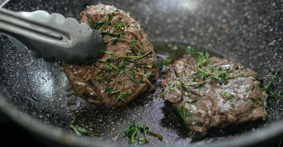 Utensils for stir frying ground beef - Juicy cutlets topped with aromatic rosemary frying in hot pan with metal tongs during cooking process in kitchen while preparing for lunch