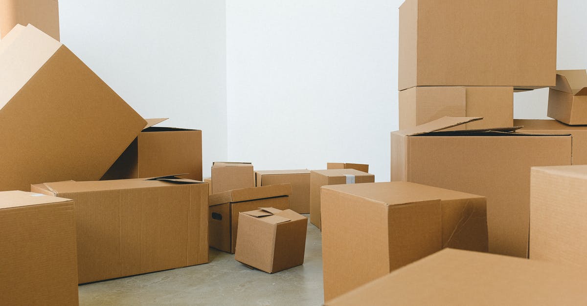 Varying pungency with size - Stack of carton boxes of various shapes and sizes scattered in floor near white walls during relocation