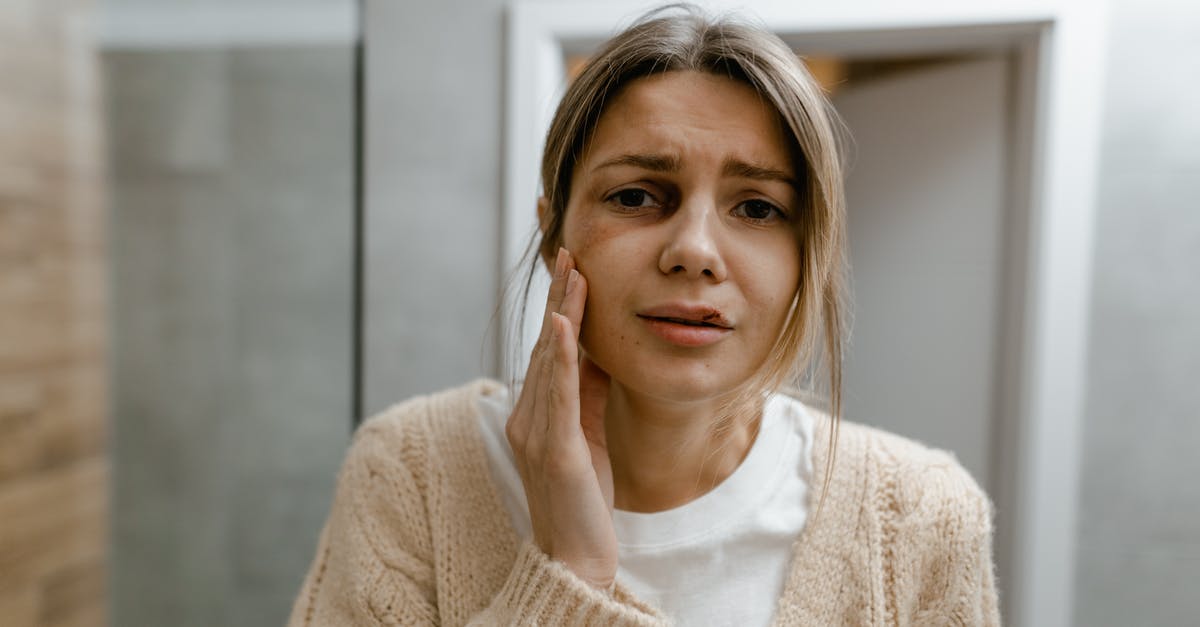 Vinegar and battered chicken? - A Woman in Beige Sweater Touching her Bruised Face