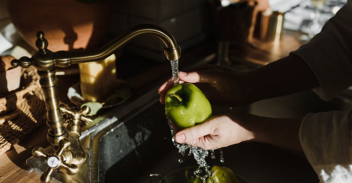 Washing fruit after cutting? - A Person Washing a Green Apple in a Sink with Running Water