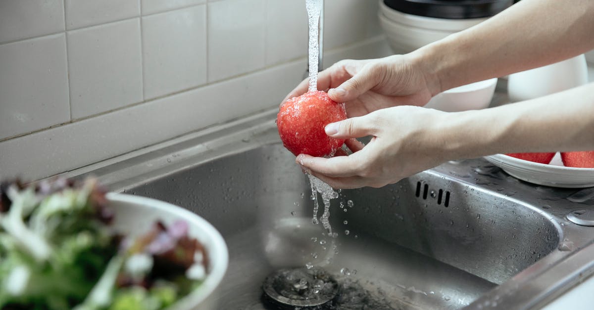 Washing fruit after cutting? - Person Washing an Apple in the Kitchen Sink