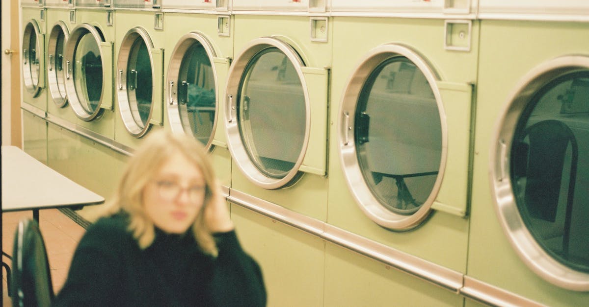 Washing Griddle before first use - Perspective view of modern washing machines in laundry room with blurred unrecognizable female in eyeglasses sitting at table in black clothes