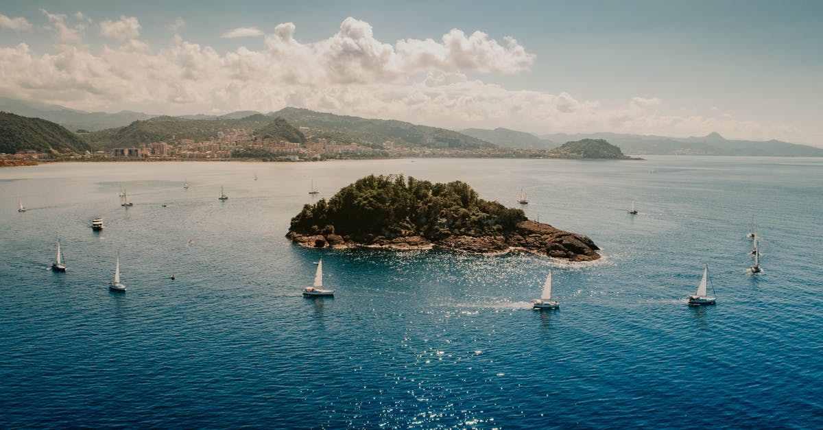 Water collects around cooked idlis in my steamer - Picturesque seascape of sailboats floating around little island in blue rippling water near hilly coast under cloudy blue sky