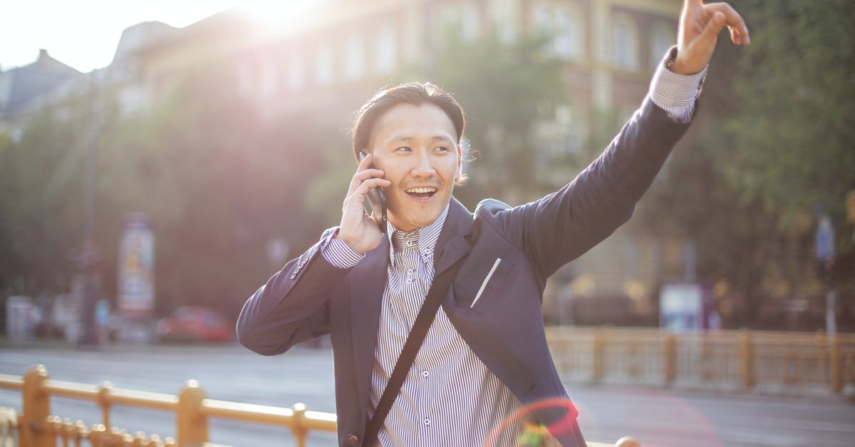 Water content of salted butter - Happy adult ethnic man in jacket waving with hand hailing taxi on sunny street while speaking on smartphone