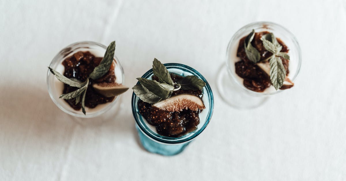 Watery liquid on top of homemade yogurt - From above of transparent glasses filled with delicious homemade dessert made of yogurt topped with jam mint leaf and slice of fig