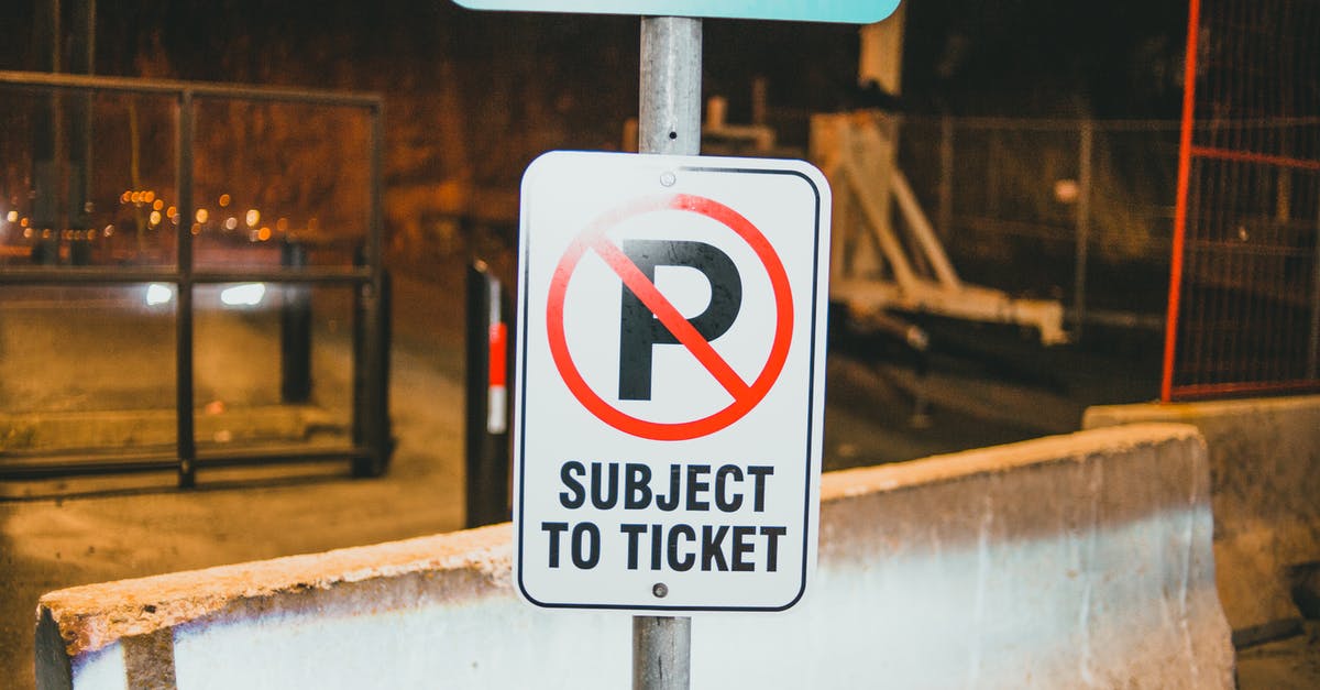 Way to Prevent Rusting Racks? - Prohibition parking road sign with Subject To Ticket inscription placed on street of city near concrete barrier in evening time