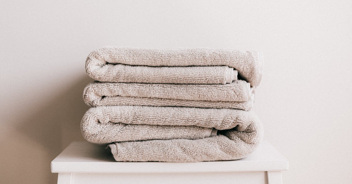 What's the best way to clean and dry blueberries? - Stack of soft clean light beige folded towels placed on white minimalist stool against beige wall in daylight