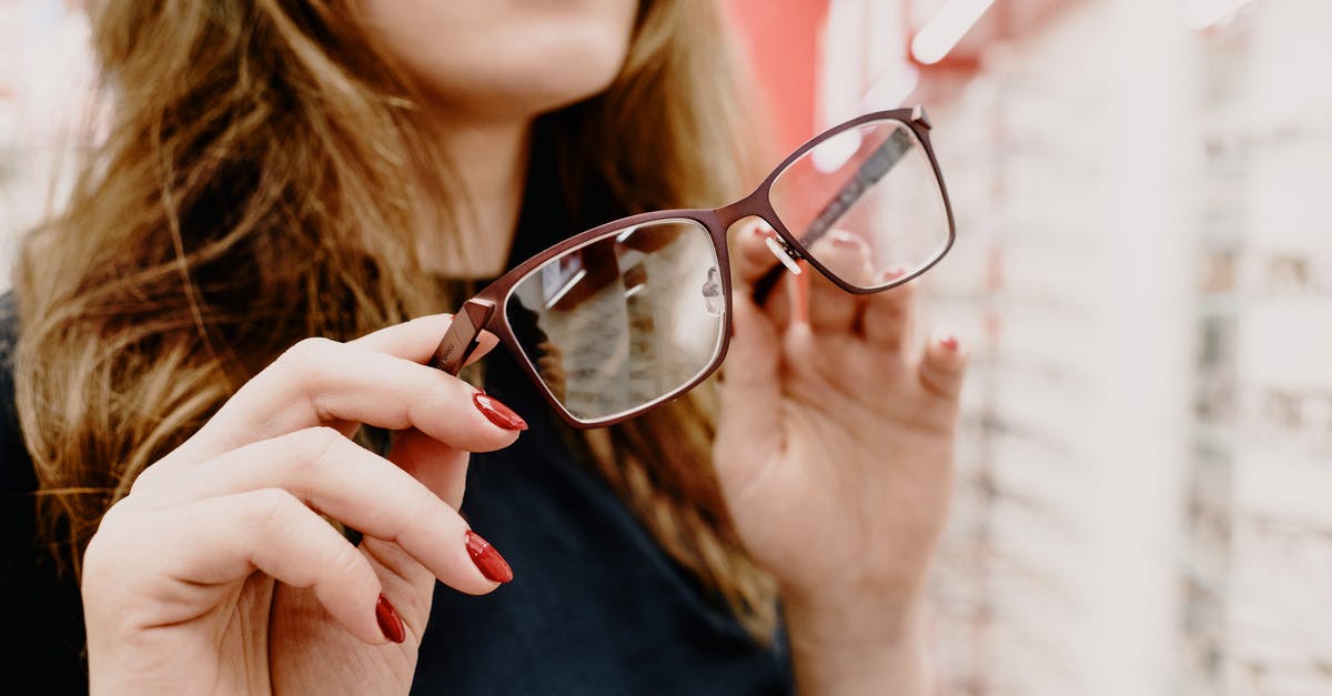 What's the correct way to store fats? - Crop female client with stylish glasses in hands picking glasses rim in optical salon