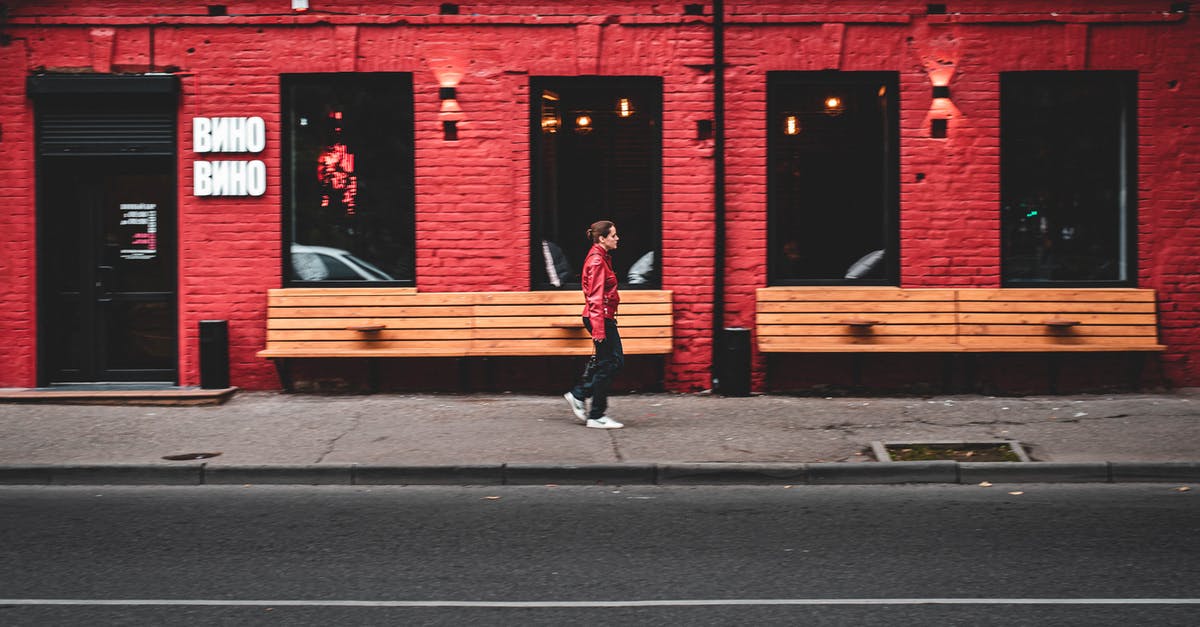 What's the correct way to store fats? - Side view of modern female walking on sidewalk near red building on city street