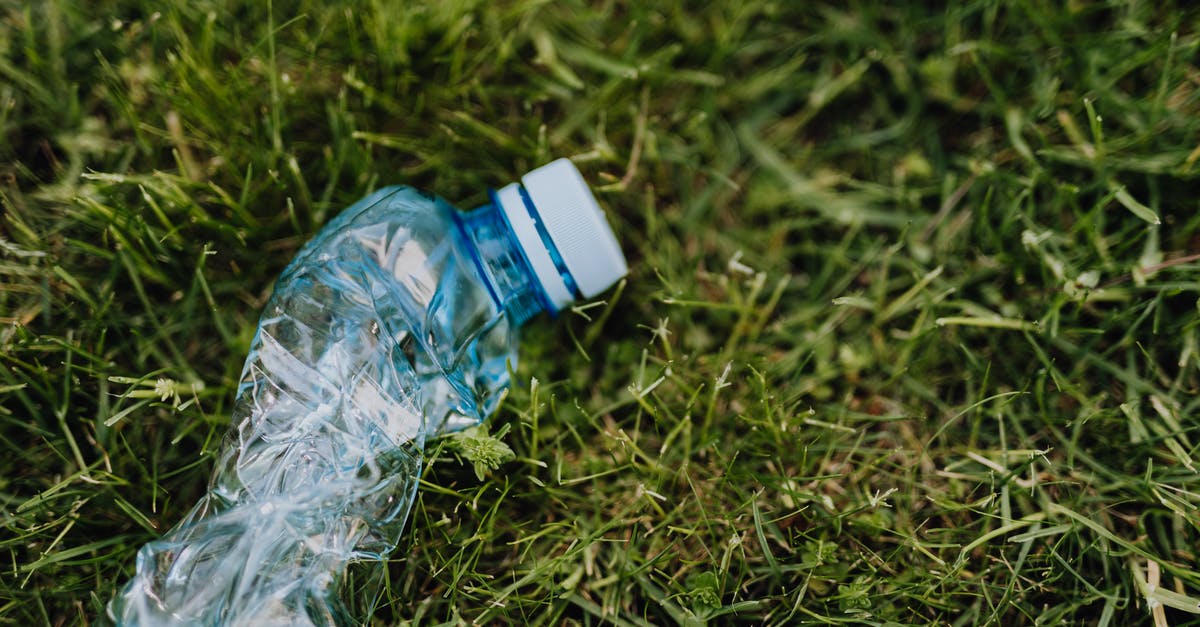 What's the proper way to dispose of used fats & oils? - From above of blue crumpled plastic bottle thrown on green park lawn on sunny summer day