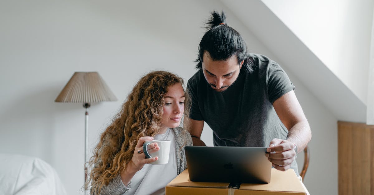 What's this odd stuff coming out of my meringue? - Concentrated young couple in casual outfit browsing netbook and packing stuff into carton boxes and suitcases to move out