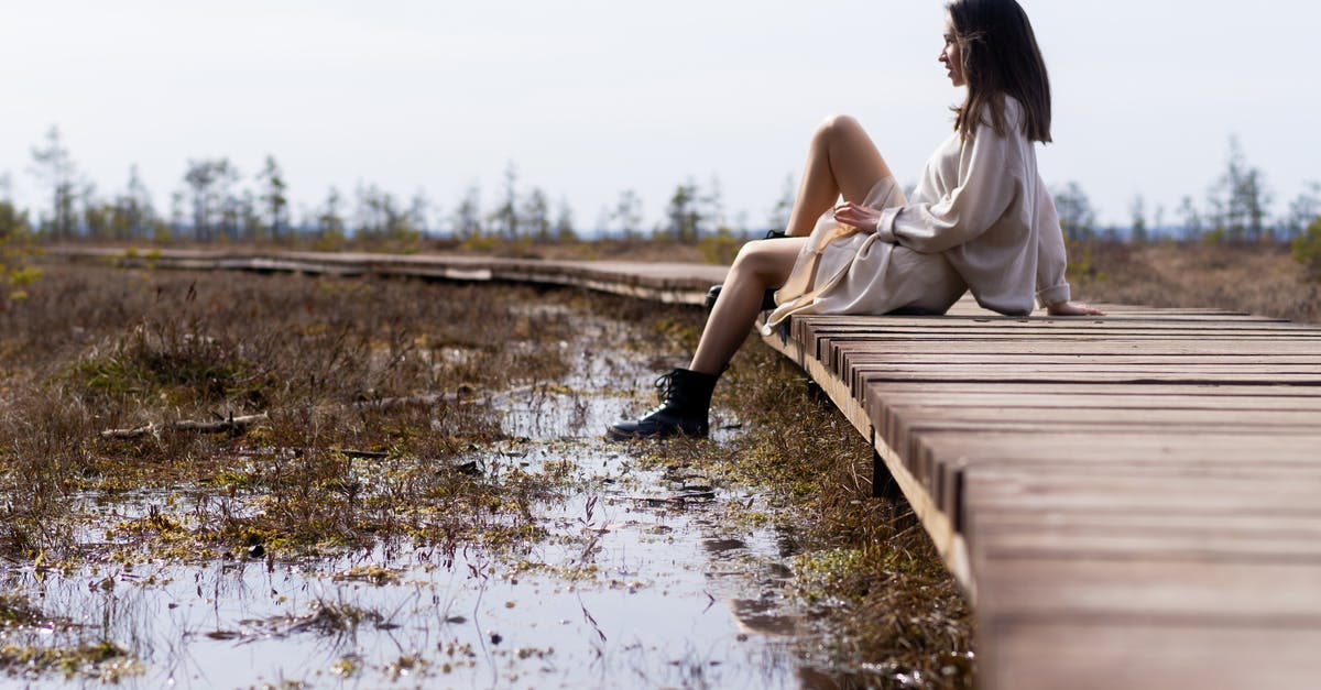 What's this salad of gray lumps in white dressing? - Woman in white dress resting on wooden path near water