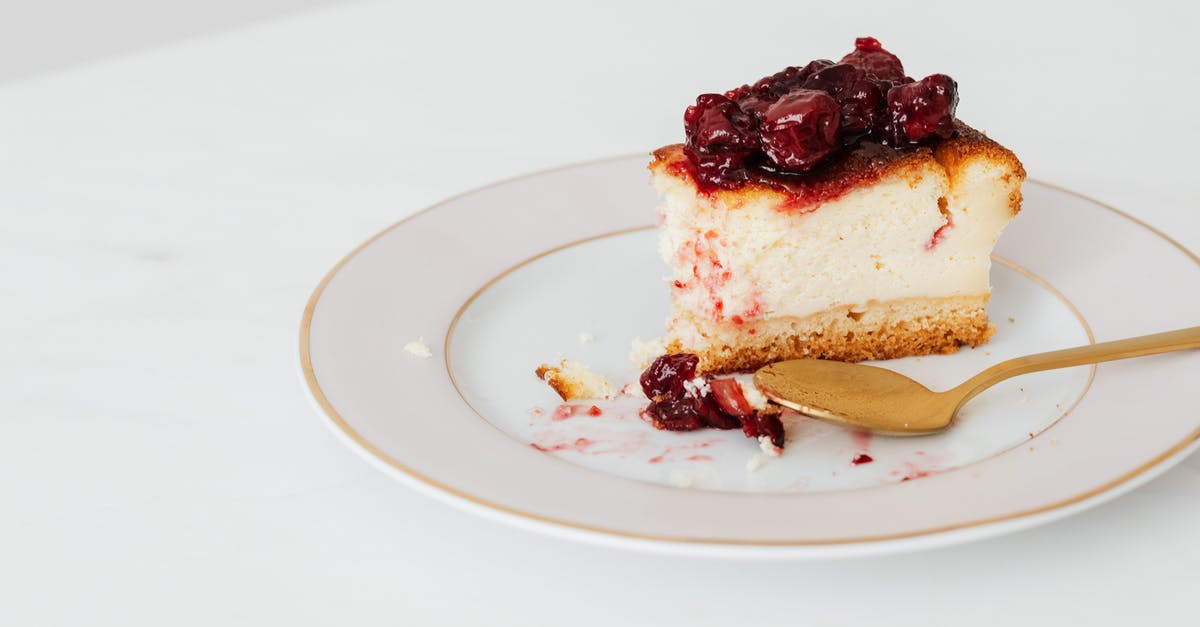 What adjustments when doubling a cheesecake recipe? - From above of bitten piece of homemade cheesecake garnishing with berry jam placed on plate with spoon