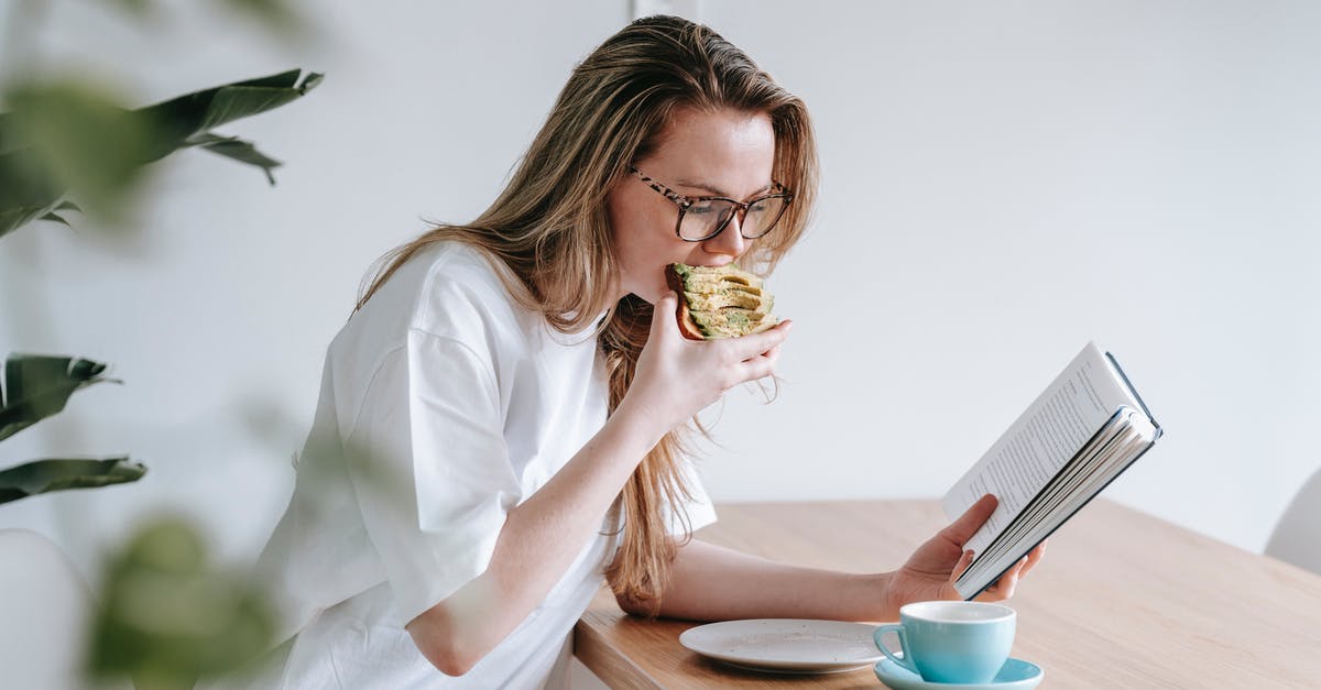 What are good resources to learn food chemistry? - Side view of smart female in eyeglasses with long hair studying book at table with cup and plate