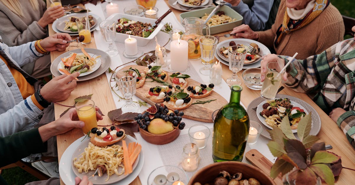 What are some kid-friendly dishes from Kenya? - From above crop people enjoying festive dinner with snacks at garden table with candles burning