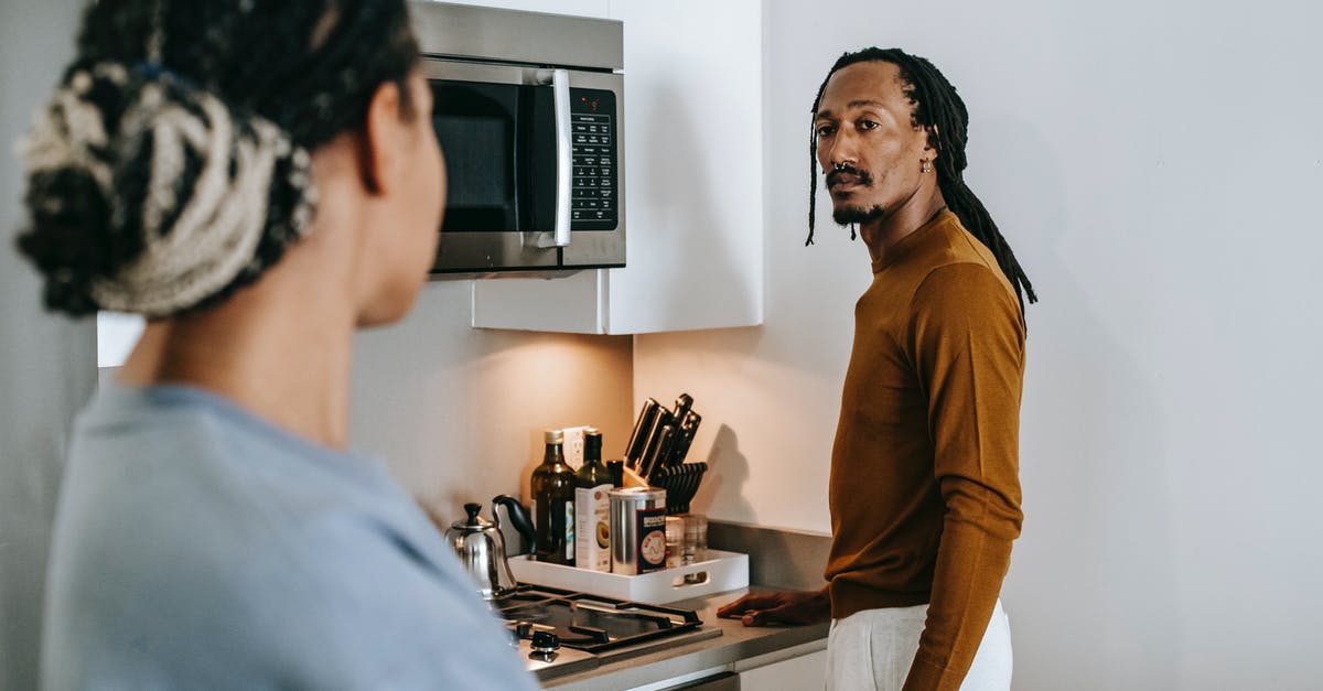 What are some of the benefits of electric stoves versus gas stoves? - Anonymous ethnic female speaking with boyfriend with dreadlocks while looking at each other in house
