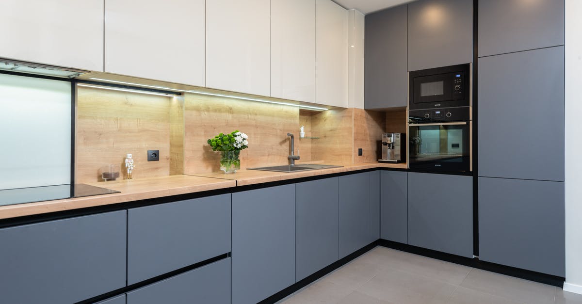 What are the benefits of stewing on the hob over cooking in the oven? - Creative design of kitchen with cupboards and built in oven against flowers in vase in light house