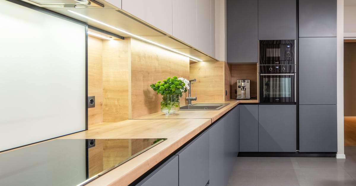 What are the benefits of stewing on the hob over cooking in the oven? - Contemporary kitchen with hob under hood built in cupboard in house with microwave oven and coffee machine