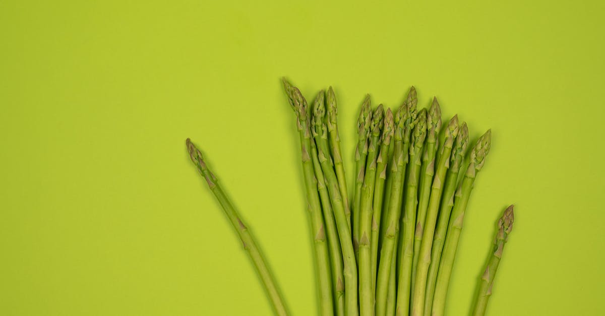 What are the conditions that raw milk, just milked from a cow, should stand to obainin thick traditional Romanian smântână? - Overhead view of fresh asparagus stalks with wavy tips in row on smooth green surface