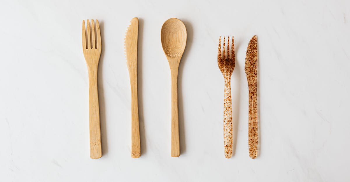 What are the pros and cons of various woods used in wooden utensils? - Top view of wooden and plastic cutlery placed in row on white marble table