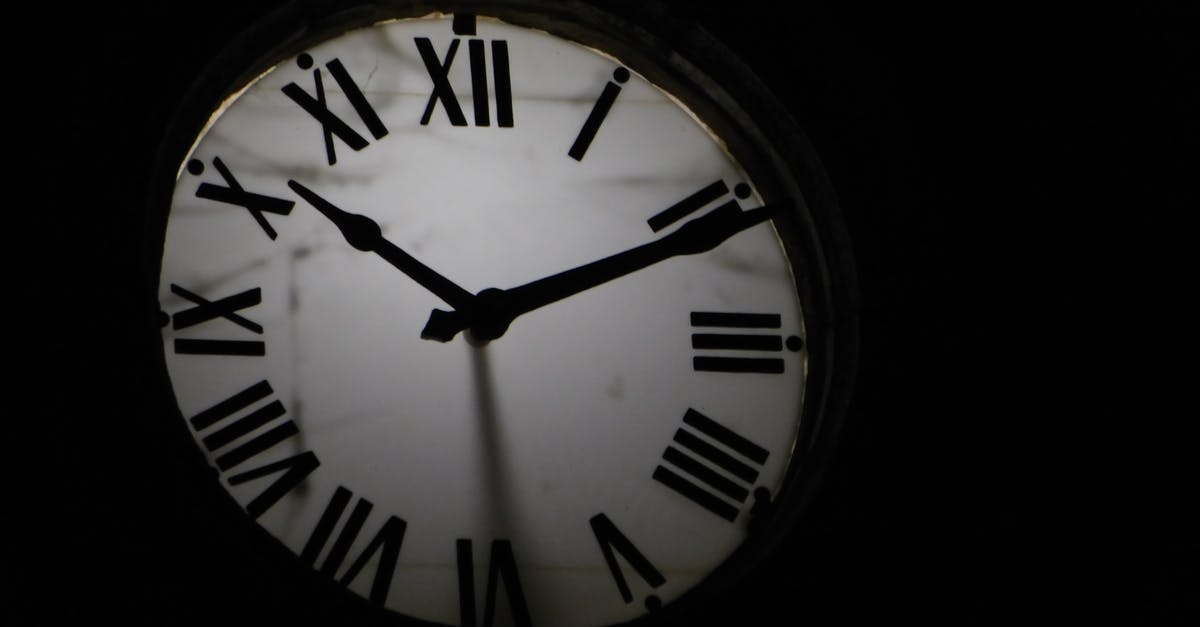 What are the signs of a watermelon past its best? - Round mechanical clock with black arrows and numbers on white face ticking on black background in darkness