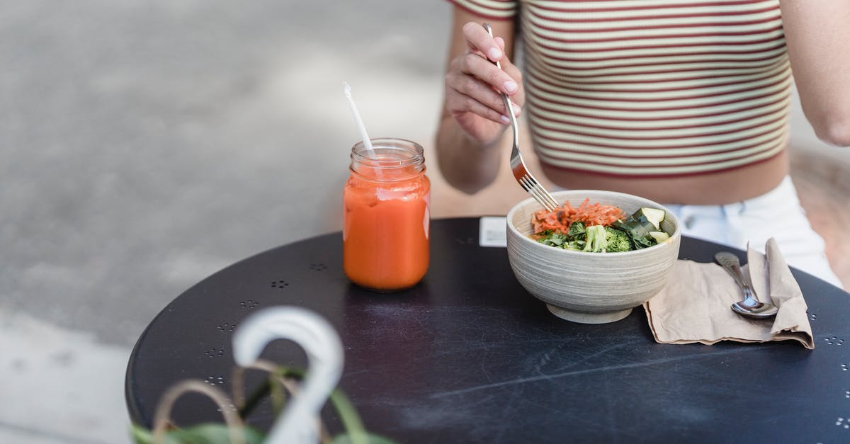 What are the transparent strands in this salad? - Crop woman with vegetable salad and smoothie in street cafeteria