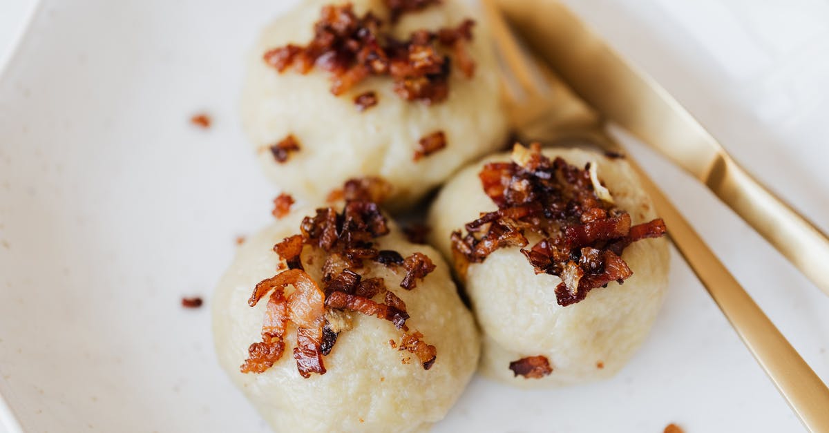 What are these crispy bits on top of rice? - Lithuanian cepelinai with fried bacon on plate