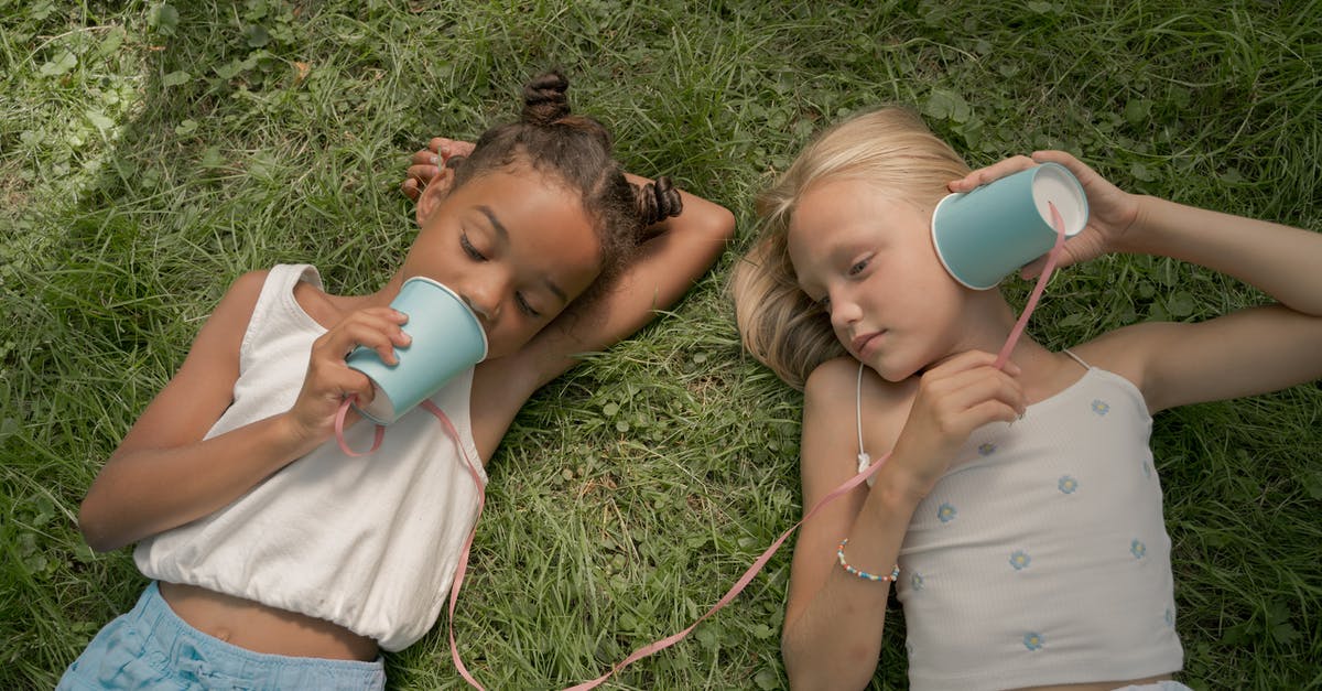 What are these two vegetables called? - Two Teenage Girls Laying on Grass and Playing Telephone Call Using Paper Cups on String