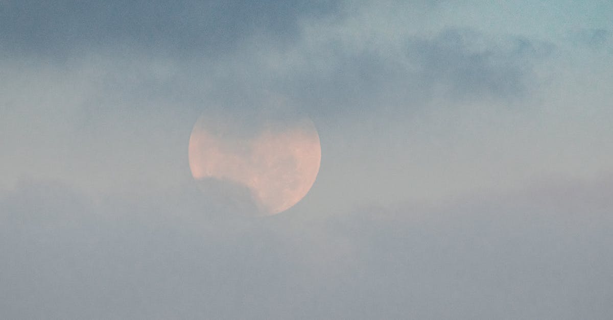 What are these white and thick things in my egg? - White moon showing through thick clouds on blue sky in gloomy weather on summer day in nature high in atmosphere